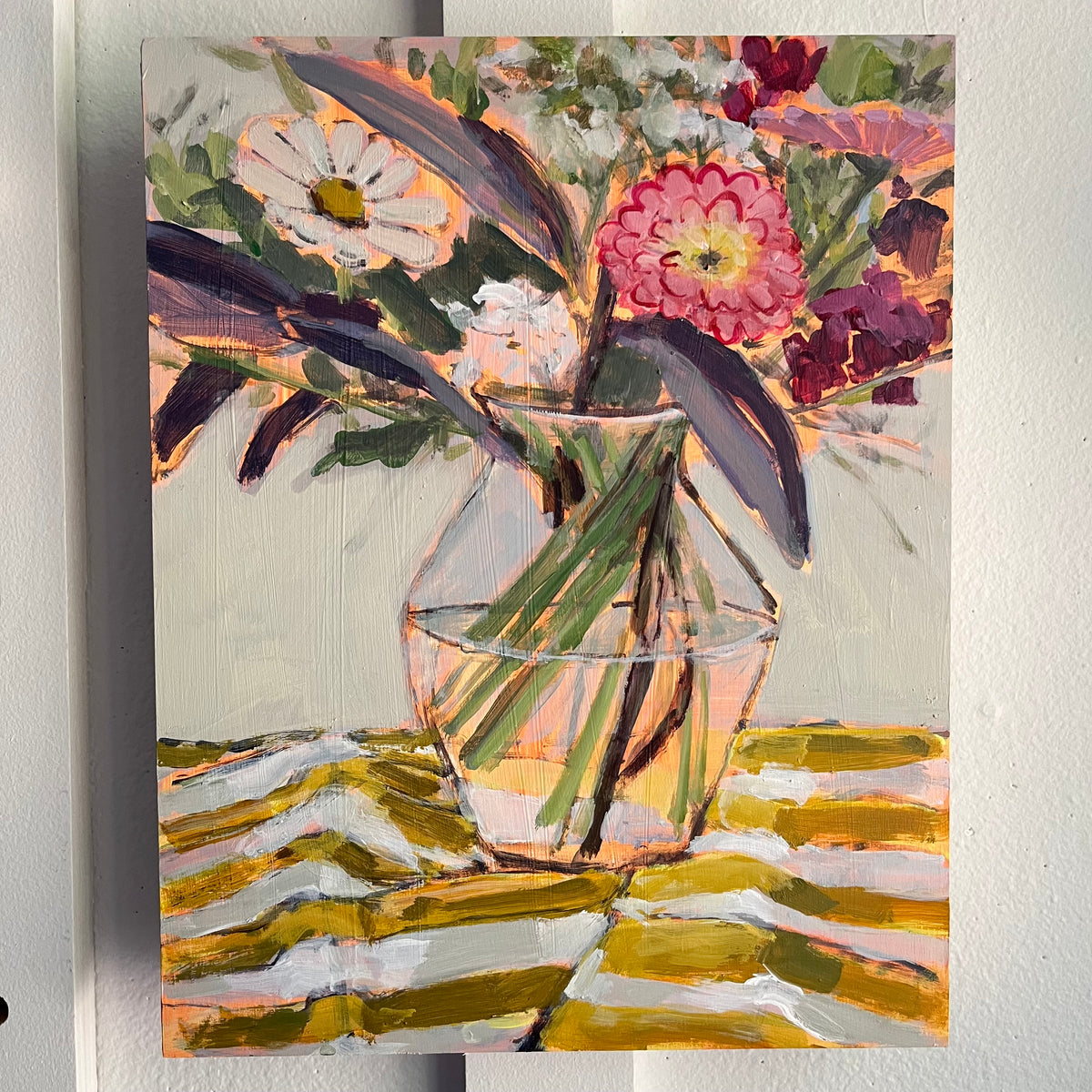 Striped Cloth — mixed flowers in a clear glass vase on a yellow-and-white striped cloth. Painting by Maggie Stickney.