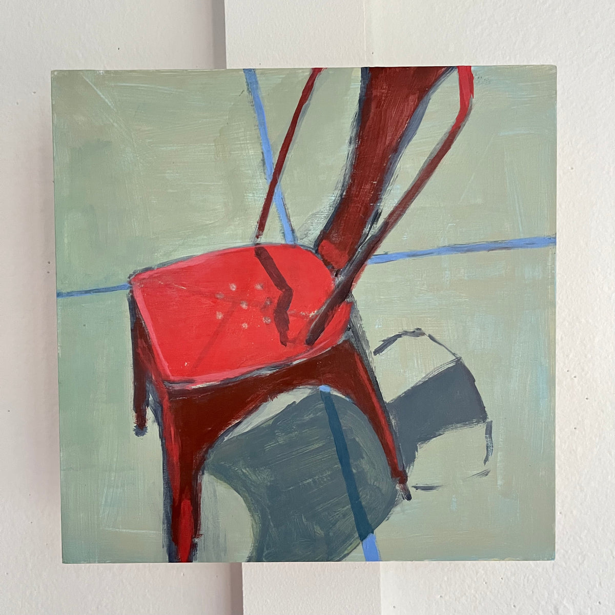Red Chair no 2 — a red metal chair casting a dark shadow across a pale green surface. Painting by Maggie Stickney.
