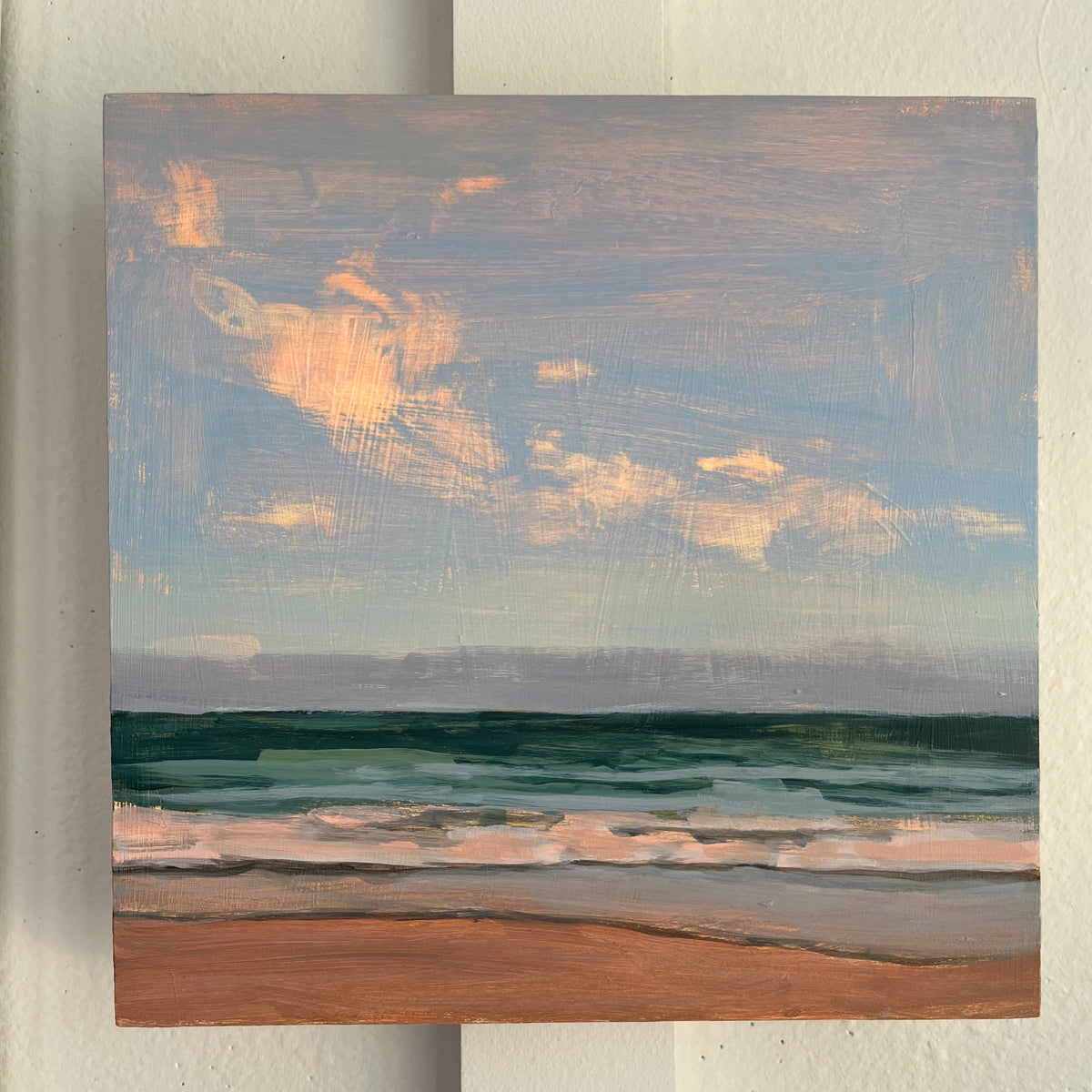 Ocean Light Study no 14 — small waves along a sandy shore beneath gray-blue clouds with warm highlights. Painting by Maggie Stickney.
