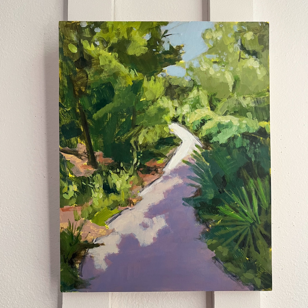Longleaf Pine Trail — a narrow curving path through dense green trees and palmettos. Painting by Maggie Stickney.