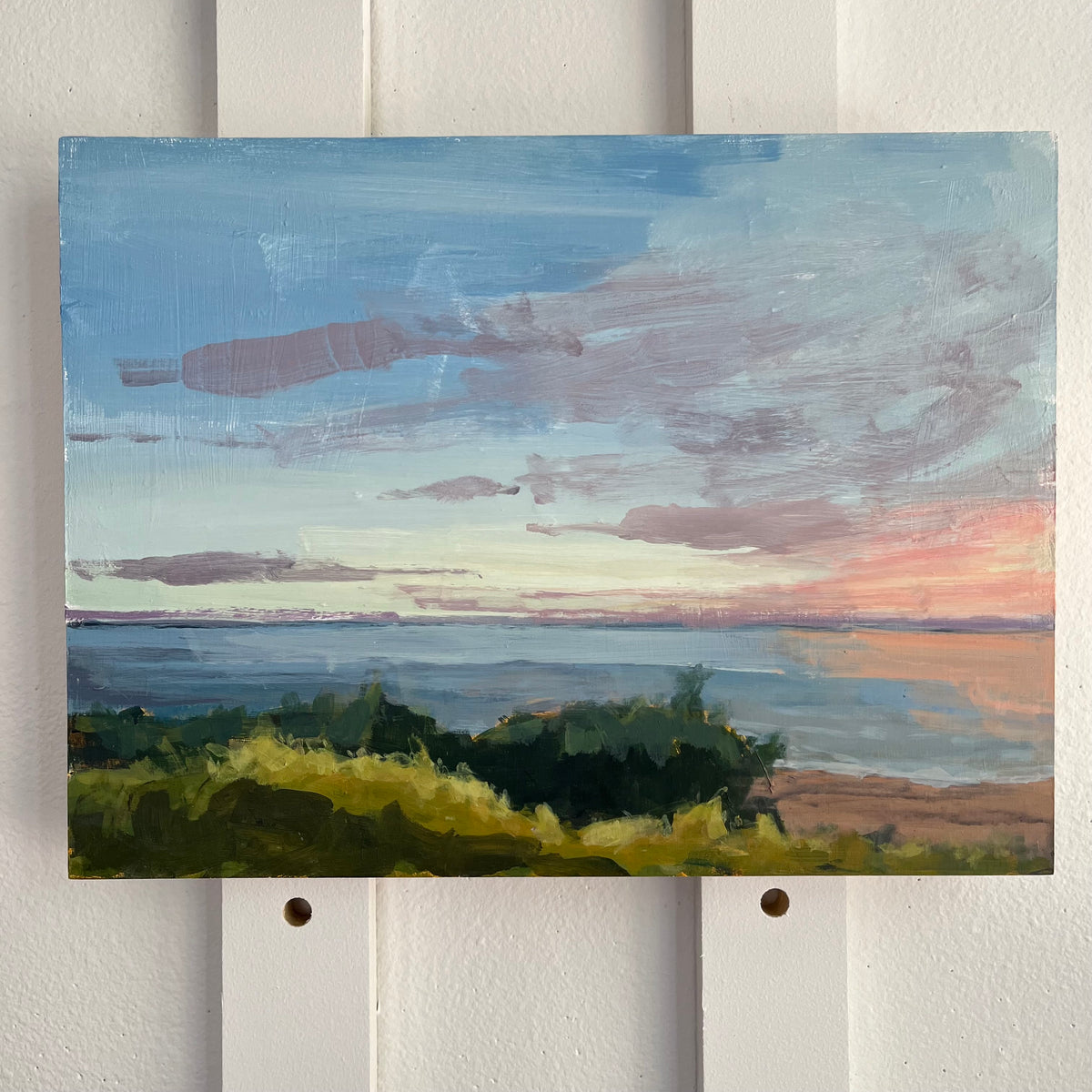 Bay Sunset no 8 — blue water and shoreline greenery beneath a blue and pink sunset sky. Painting by Maggie Stickney.