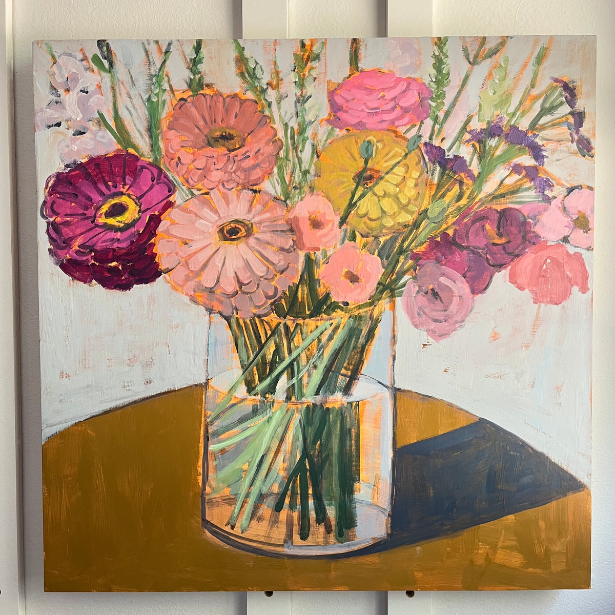 Farmers Market Bouquet — pink, purple, and peach flowers in a clear vase on a golden tabletop. Painting by Maggie Stickney.