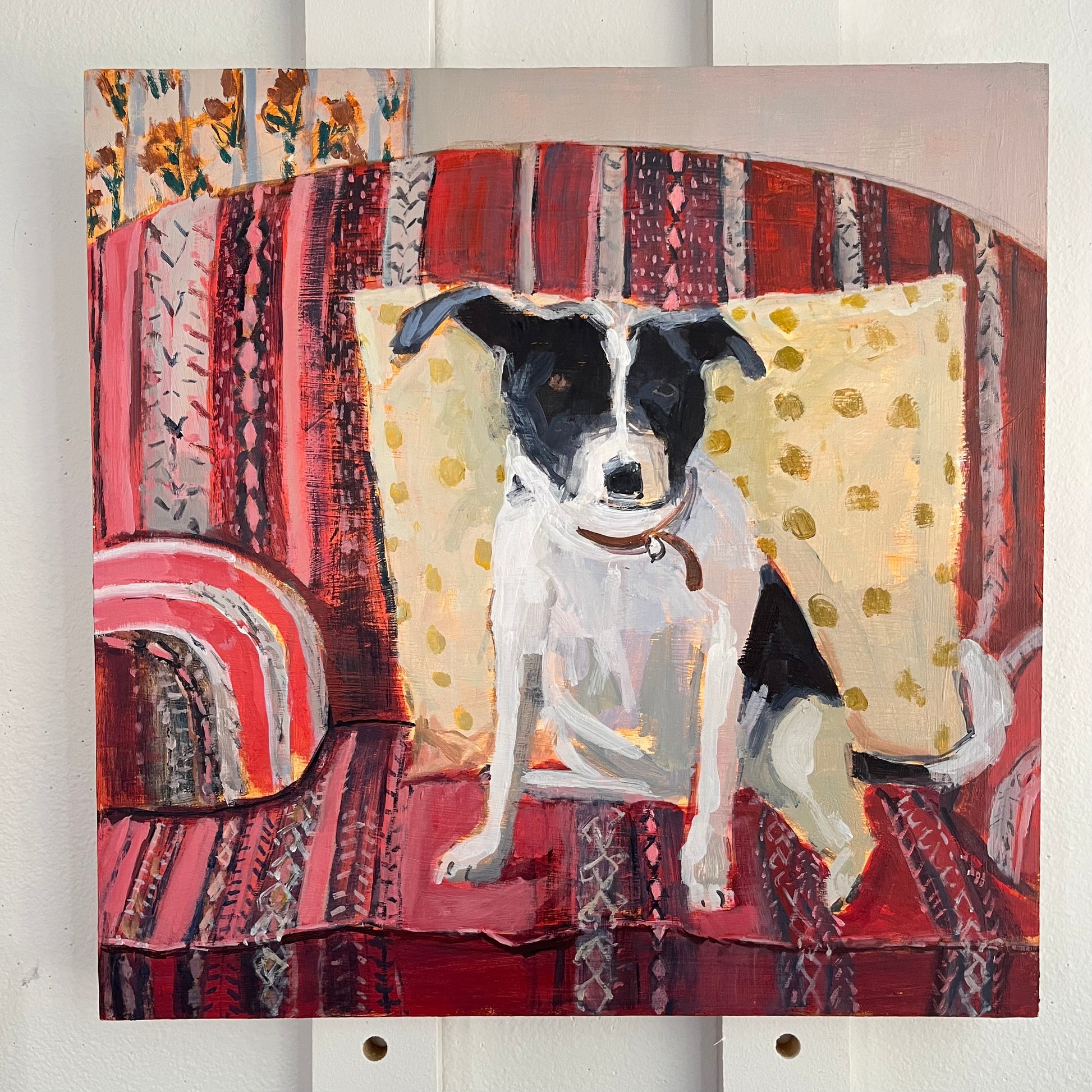 Dog on Red Chair — a black and white dog sitting on a red patterned chair with a yellow cushion. Painting by Maggie Stickney.